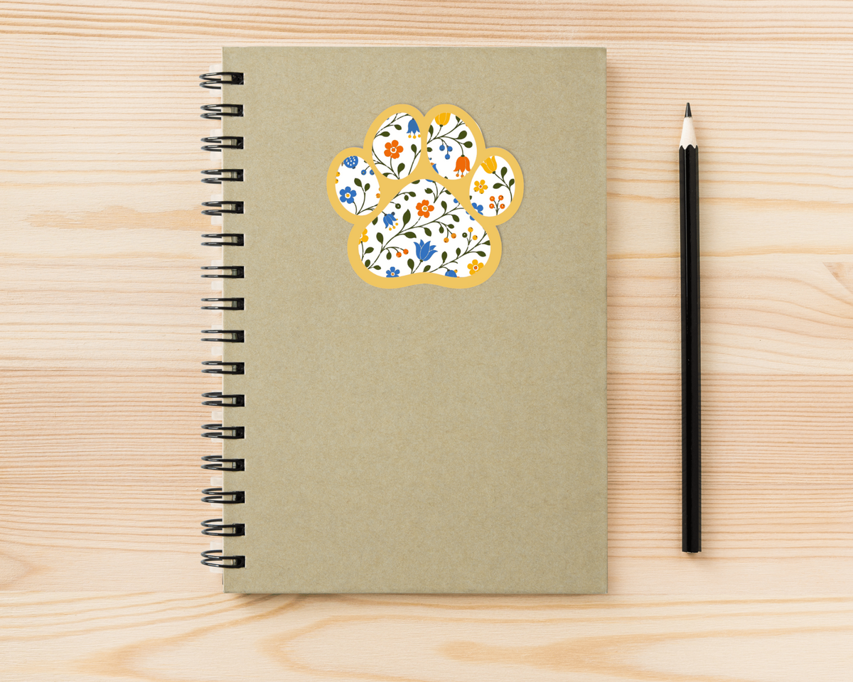 Goldenrod Floral Paw Print Sticker on a spiral notebook